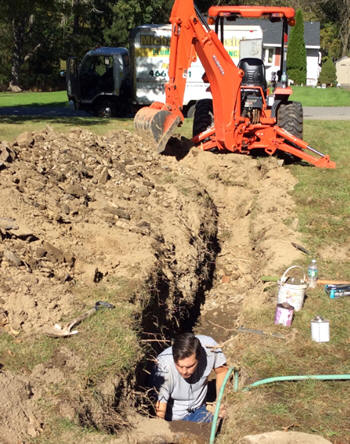 A man is digging a hole in the ground with a hose.