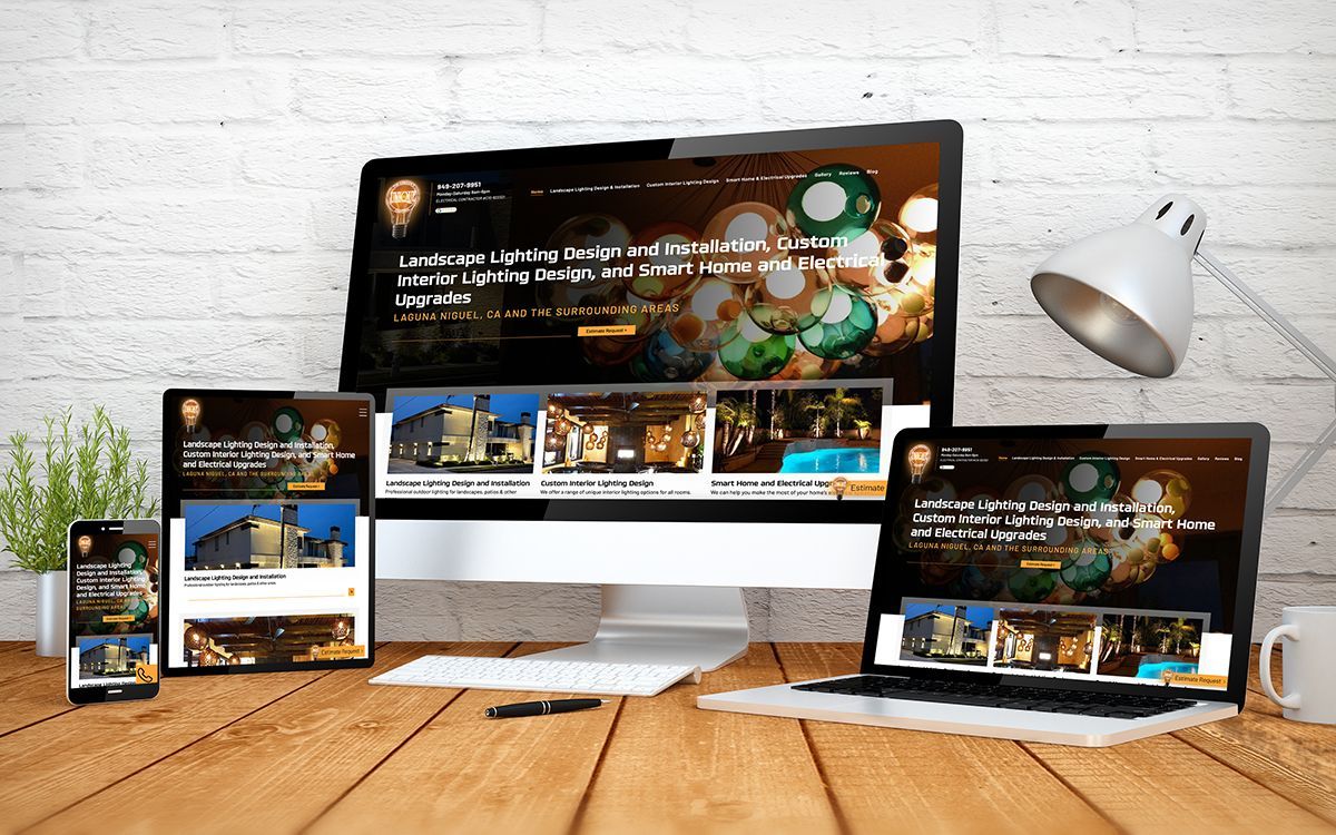 Website displayed on multiple devices: desktop, laptop, tablet, and phone, on a wooden desk.