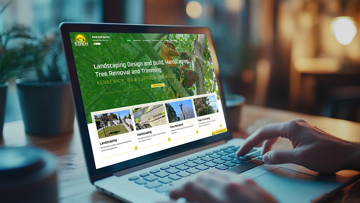 Person using a laptop displaying a website with a green and gold nature theme in a cafe setting.