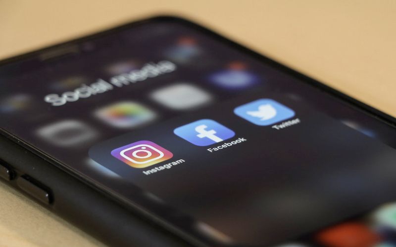 A close up of a cell phone with social media icons on the screen.