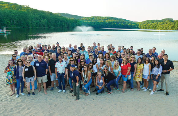 A large group of people are posing for a picture under a tree.