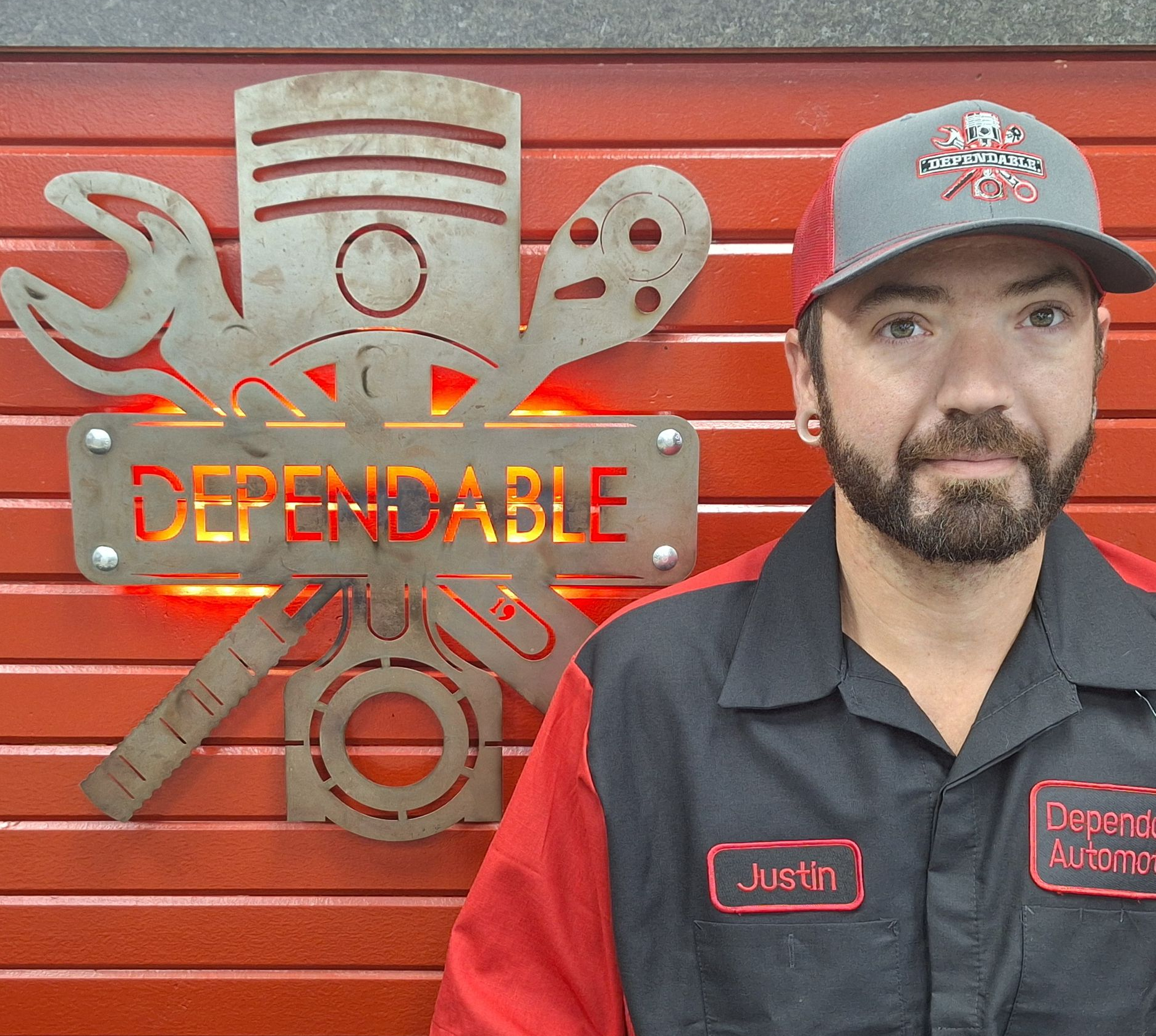 Mechanic in black and red uniform beside a red tool chest with “Dependable” emblem | Dependable Automotive