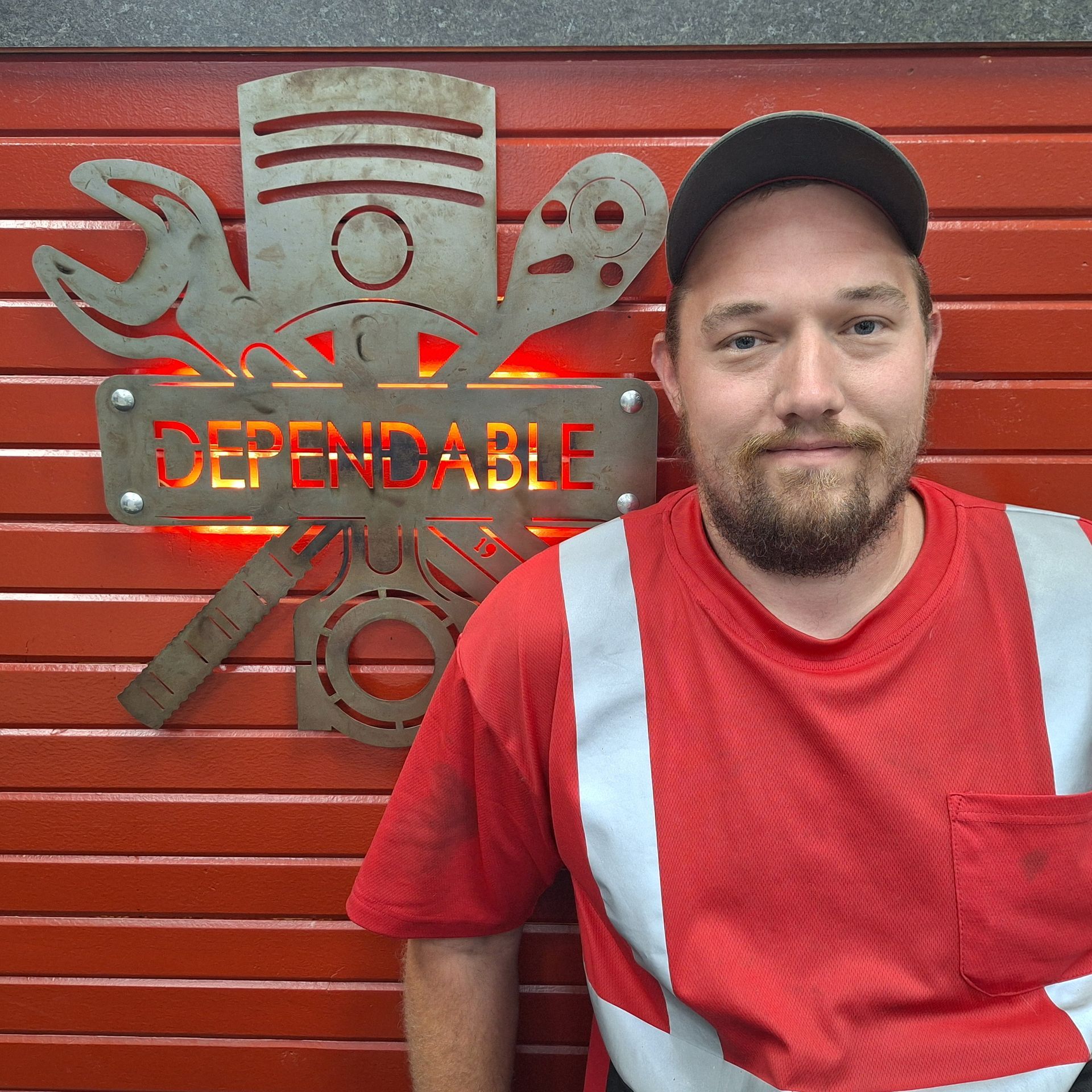 Firefighter in navy uniform standing before a red garage door with a fire department emblem. | Dependable Automotive