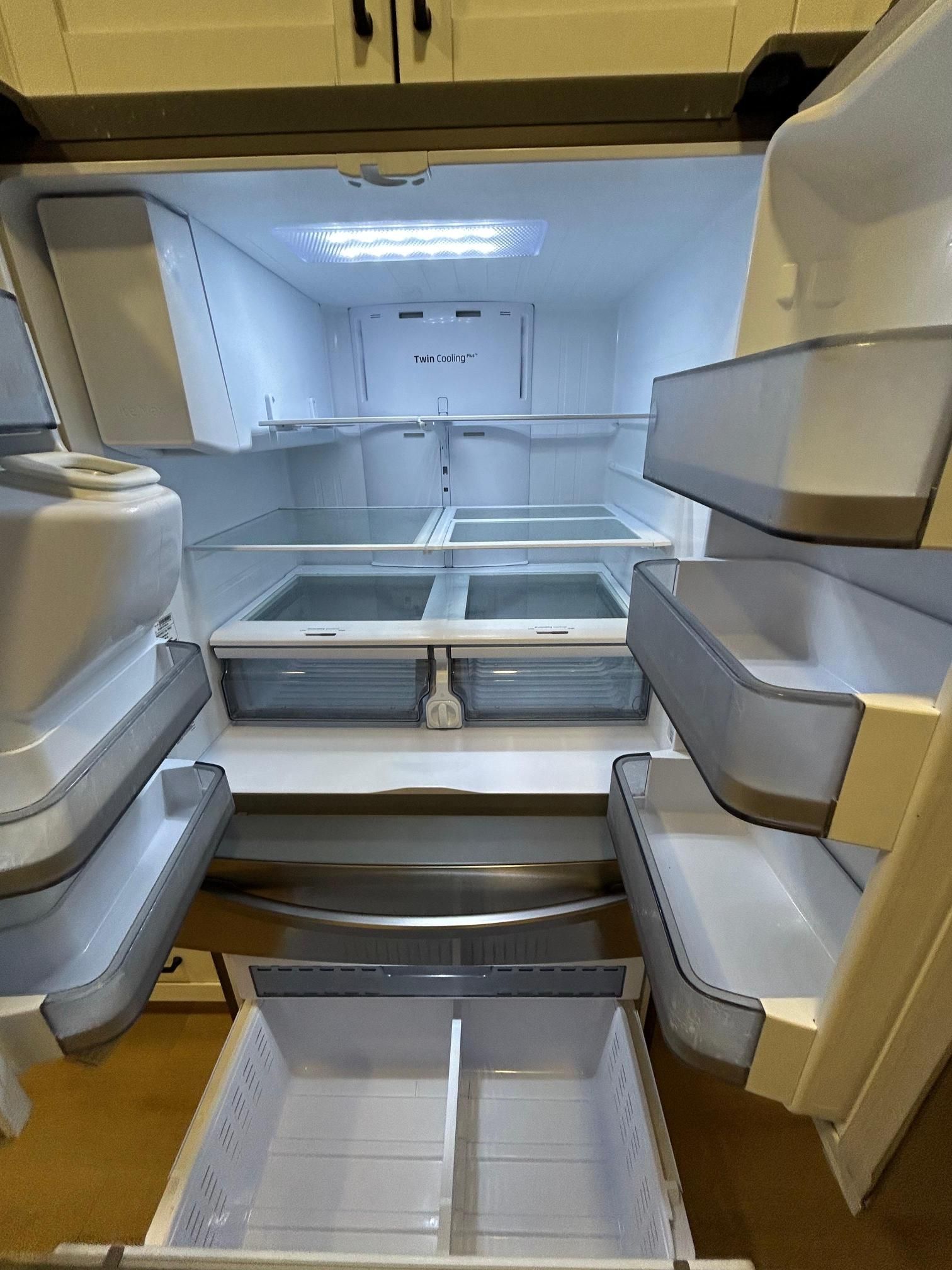 An empty refrigerator interior, shelves and drawers visible. Bright overhead lighting.
