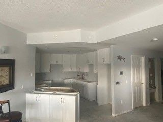A kitchen with white cabinets and a clock on the wall.