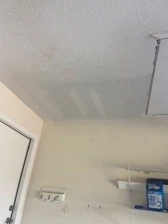 A white ceiling in a room with a door and a shelf.