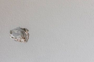 A man is kneeling down and painting a wall with a spatula.