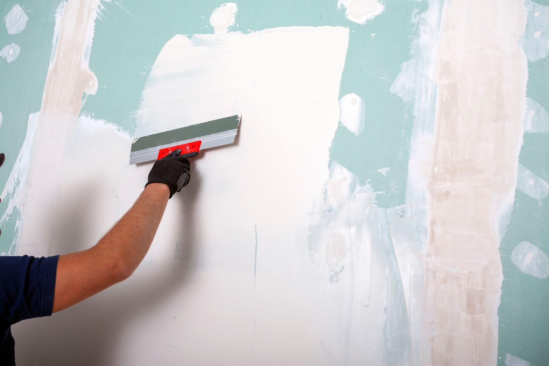 A man is plastering a wall with a spatula.