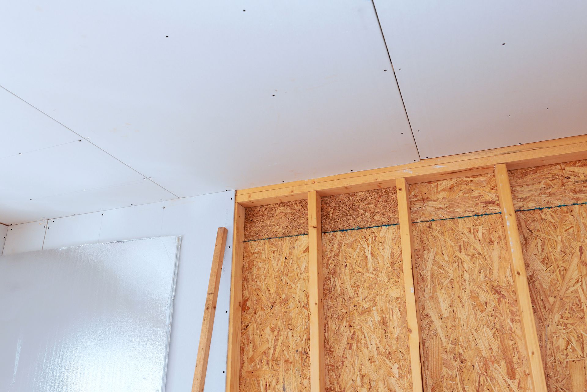 A man is standing next to a ladder in an empty room.