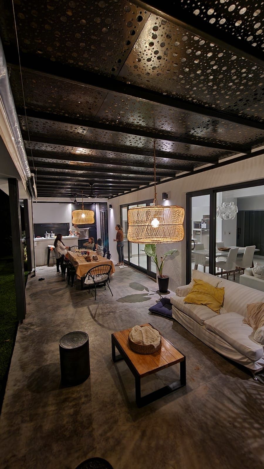 Una sala de estar con sofá, mesa y sillas por la noche.