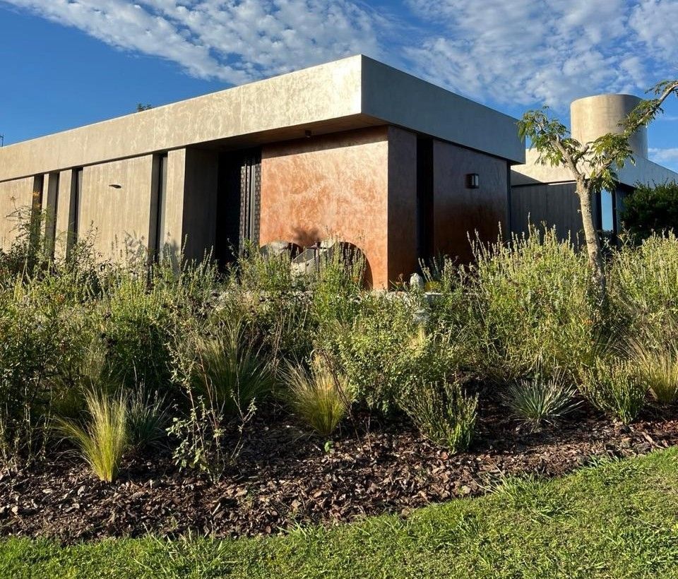 Una casa grande con una torre de agua delante de ella está rodeada de césped y arbustos.