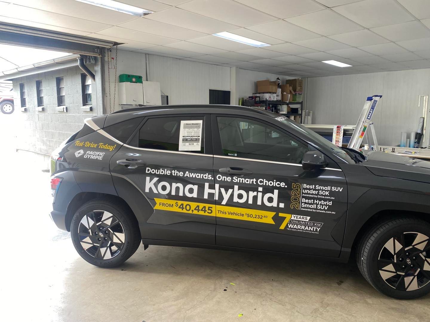 Black Hyundai Kona Hybrid in a Garage, With Promotional Text on the Side — Boss Signs & Tint in Gympie, QLD