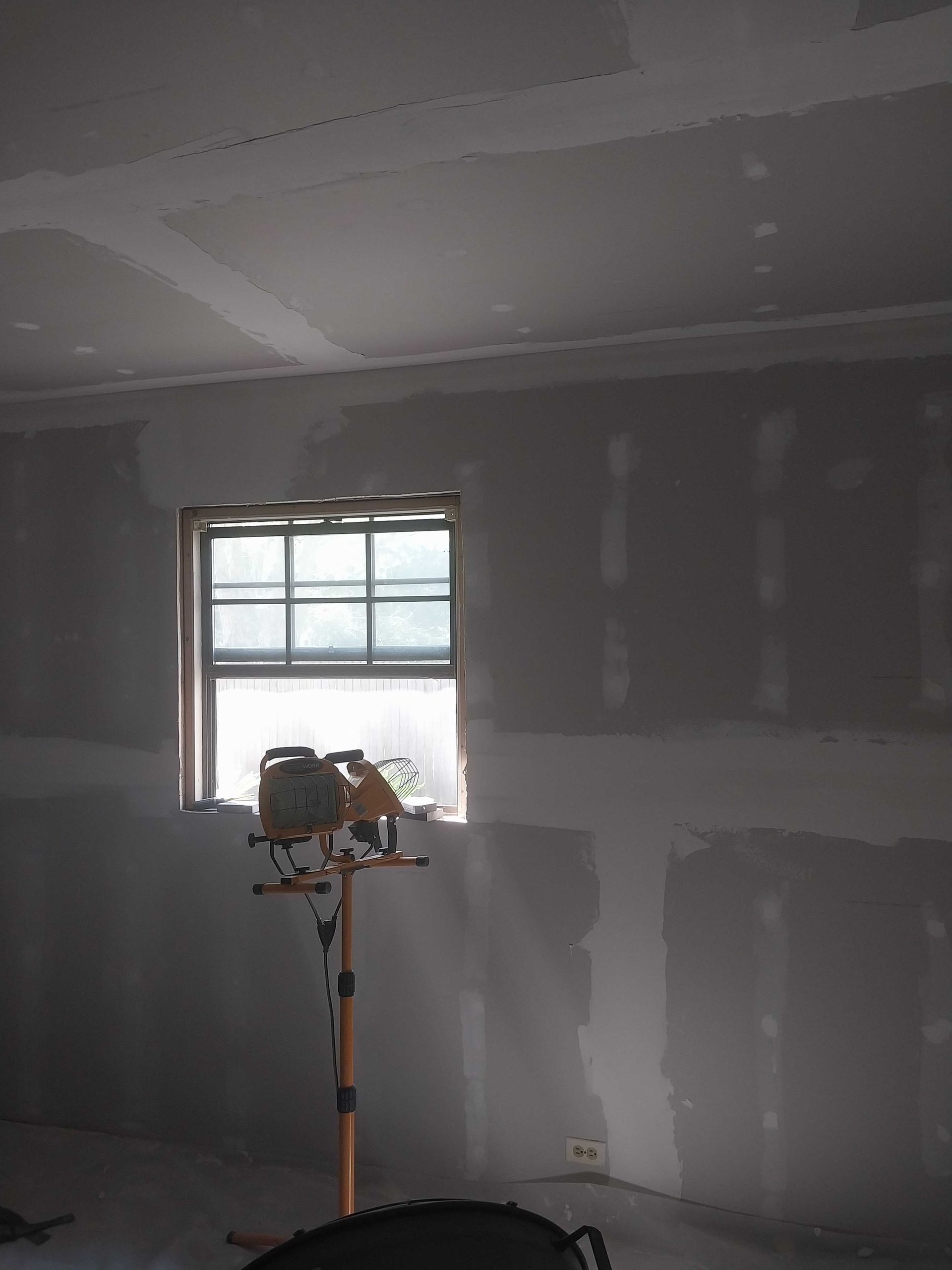 A room in a house under construction with drywall and windows.