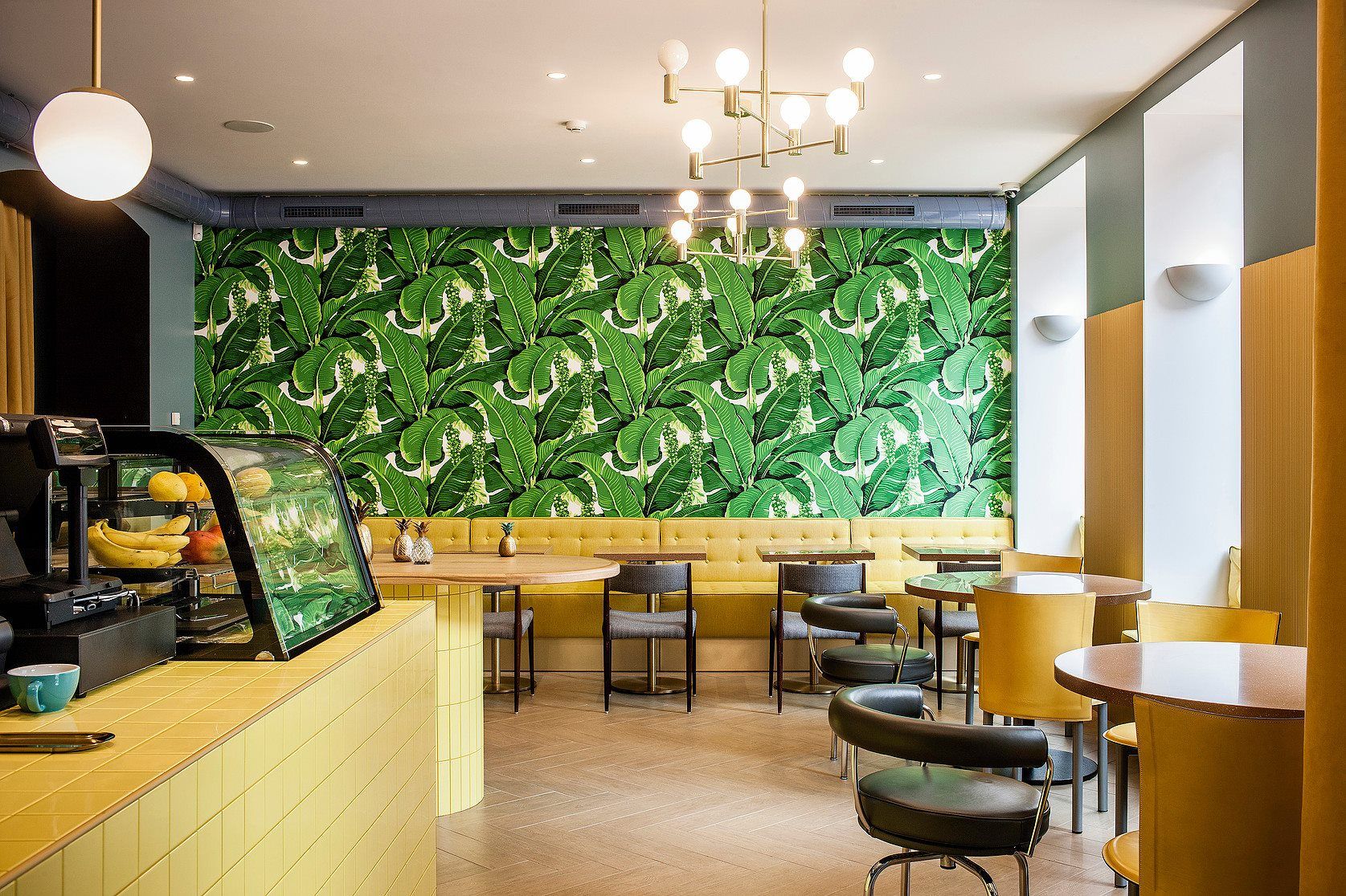 galdiņi ar krēsliem un zaļu sienu