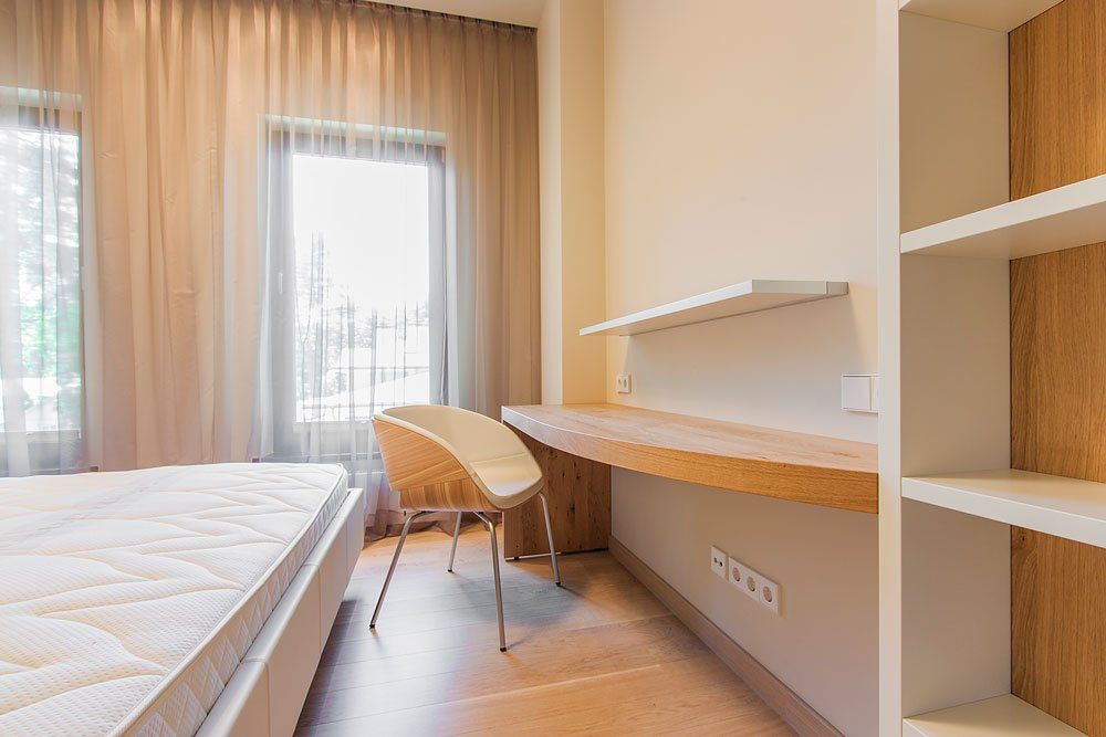 gaiša guļamistaba ar gaišu krēslu un galdu