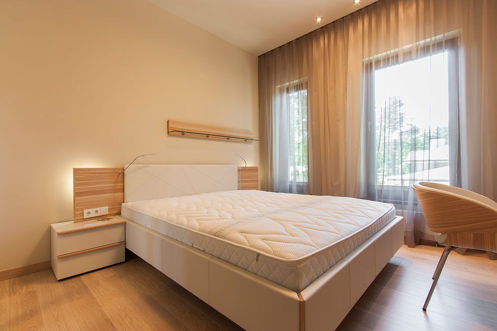 gaiša guļamistaba ar divvietīgo gultu un gaišu naktsskapīti