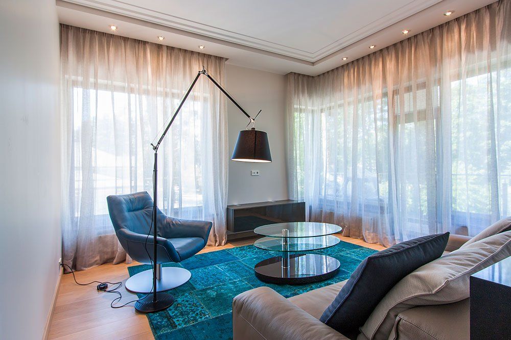 dzīvojamā istaba ar stāvlampu, mīkstajiem krēsliem un zilu paklāju