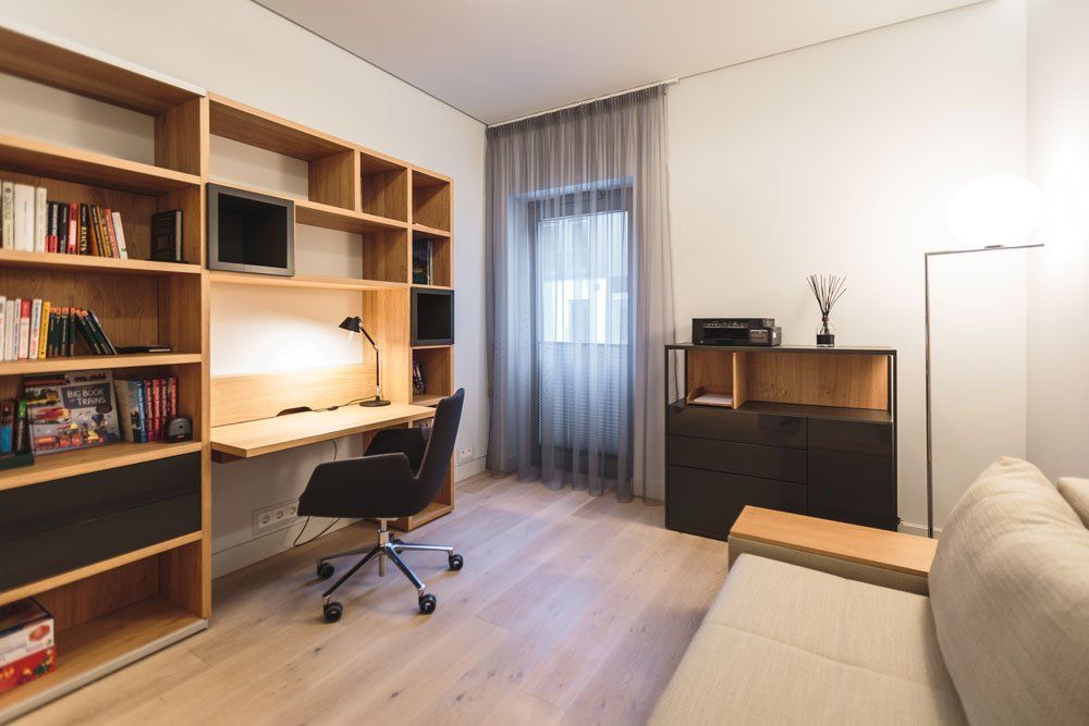 darba istaba ar rakstāmgaldu, biroja krēslu un dīvānu