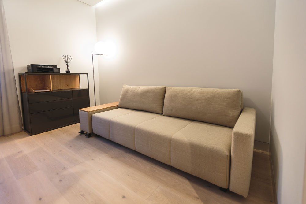 dzeltens dīvāns, stāvlampa un melna kumode