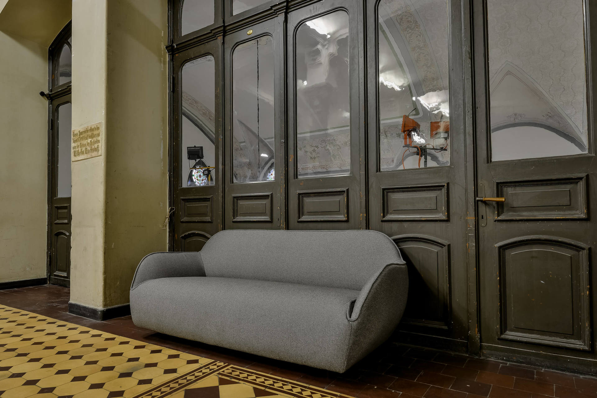 pelēks auduma dīvāns pie durvīm