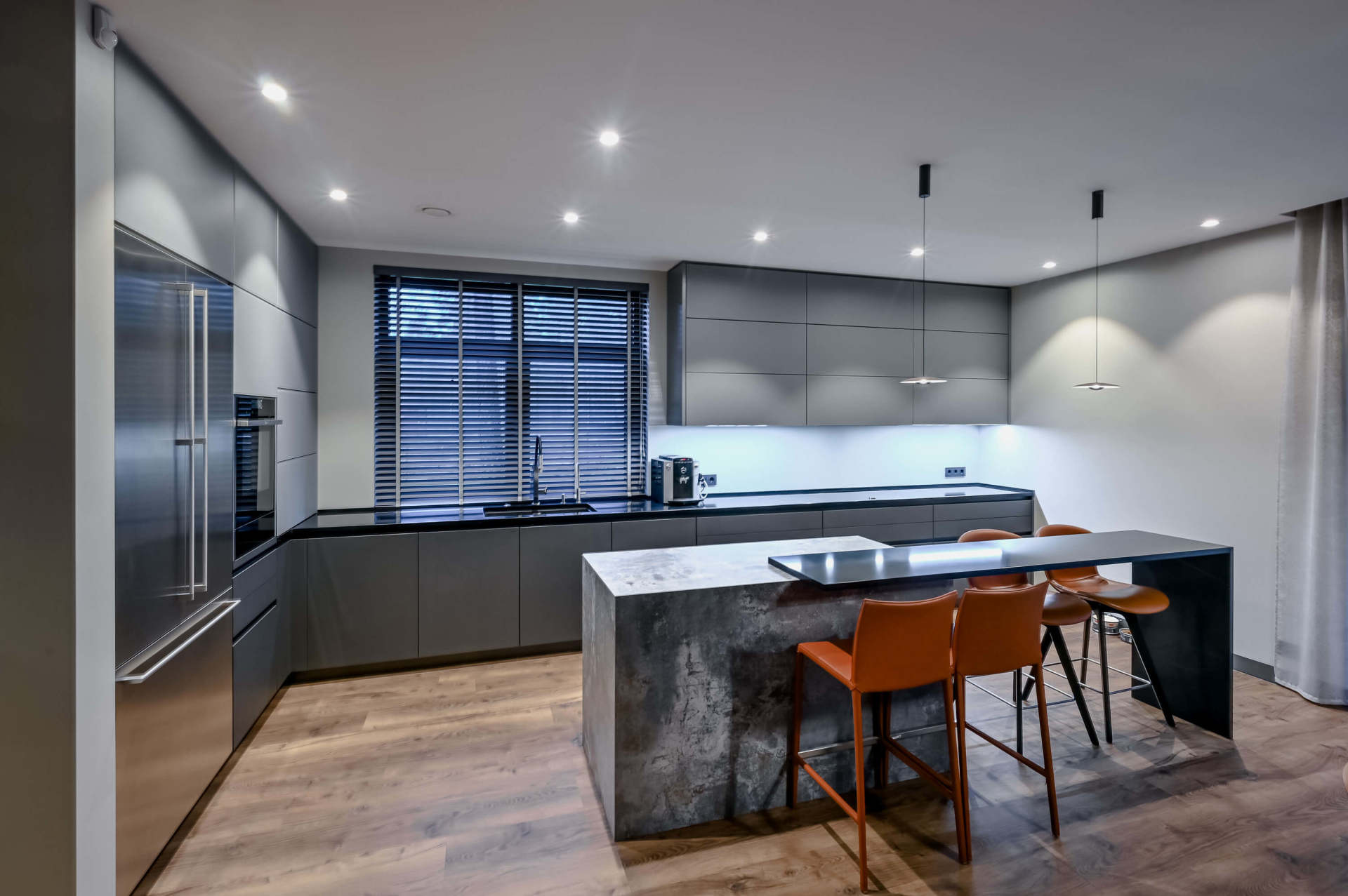 pelēks virtuves galds ar oranžiem virtuves krēsliem
