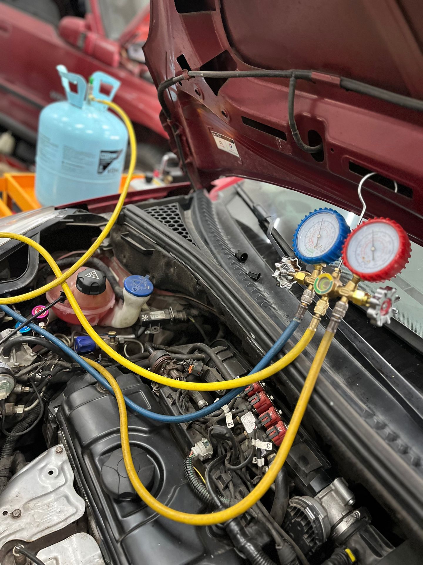 Compartimiento del motor del automóvil con medidores conectados a mangueras y un tanque de refrigerante azul
