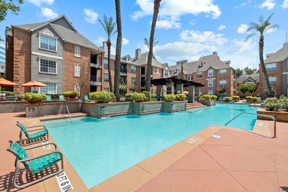 a large swimming pool in front of a building with palm trees at Marquis on Pin Oak in Houston, TX.
