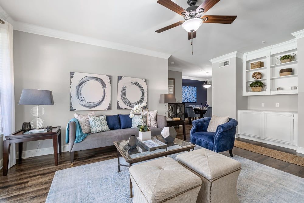 a living room with a couch, chairs, ottomans, and a ceiling fan at Marquis on Pin Oak in Houston, TX.