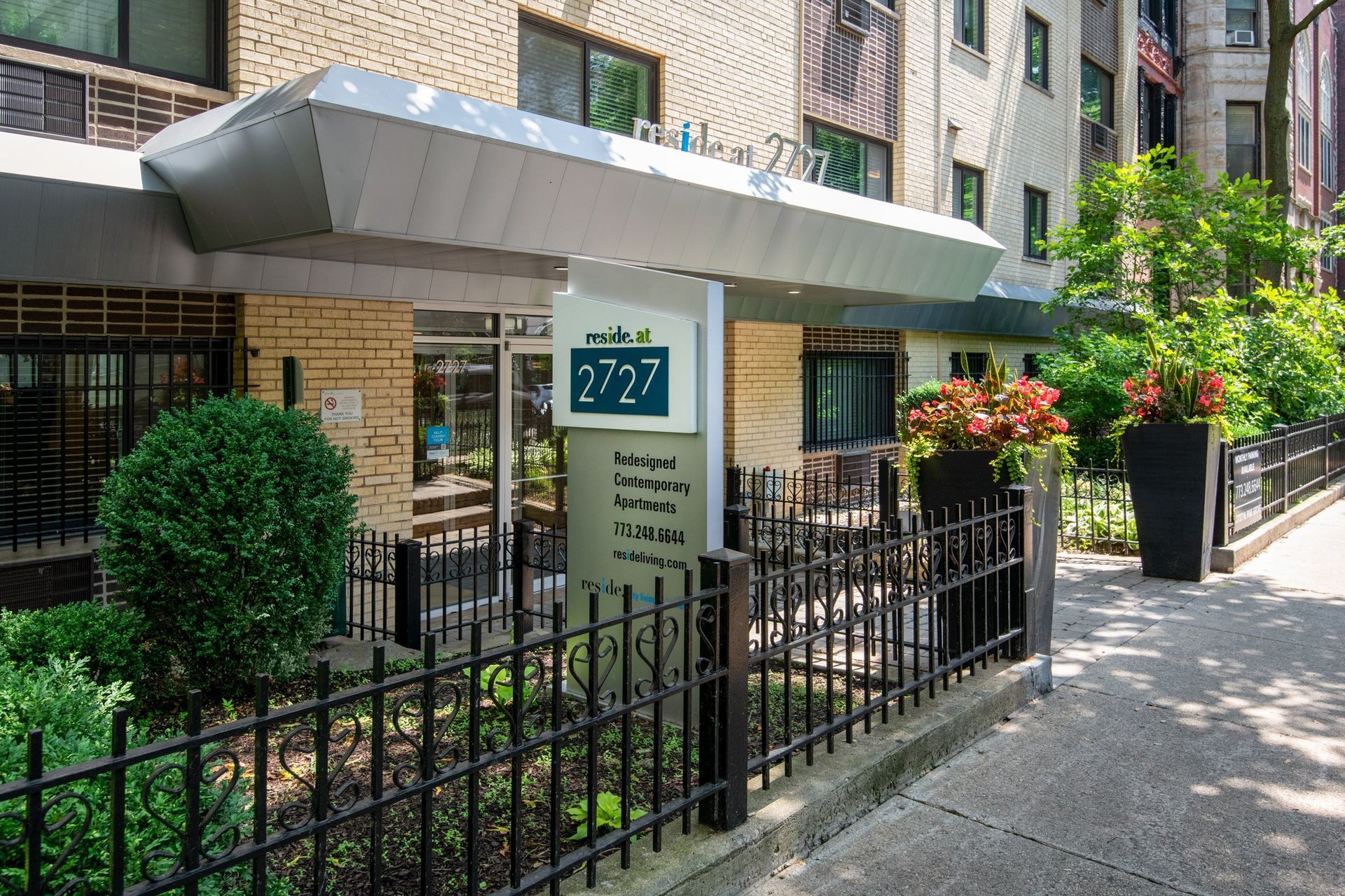 Outside of the building of Reside at 2727 showing sign and fence