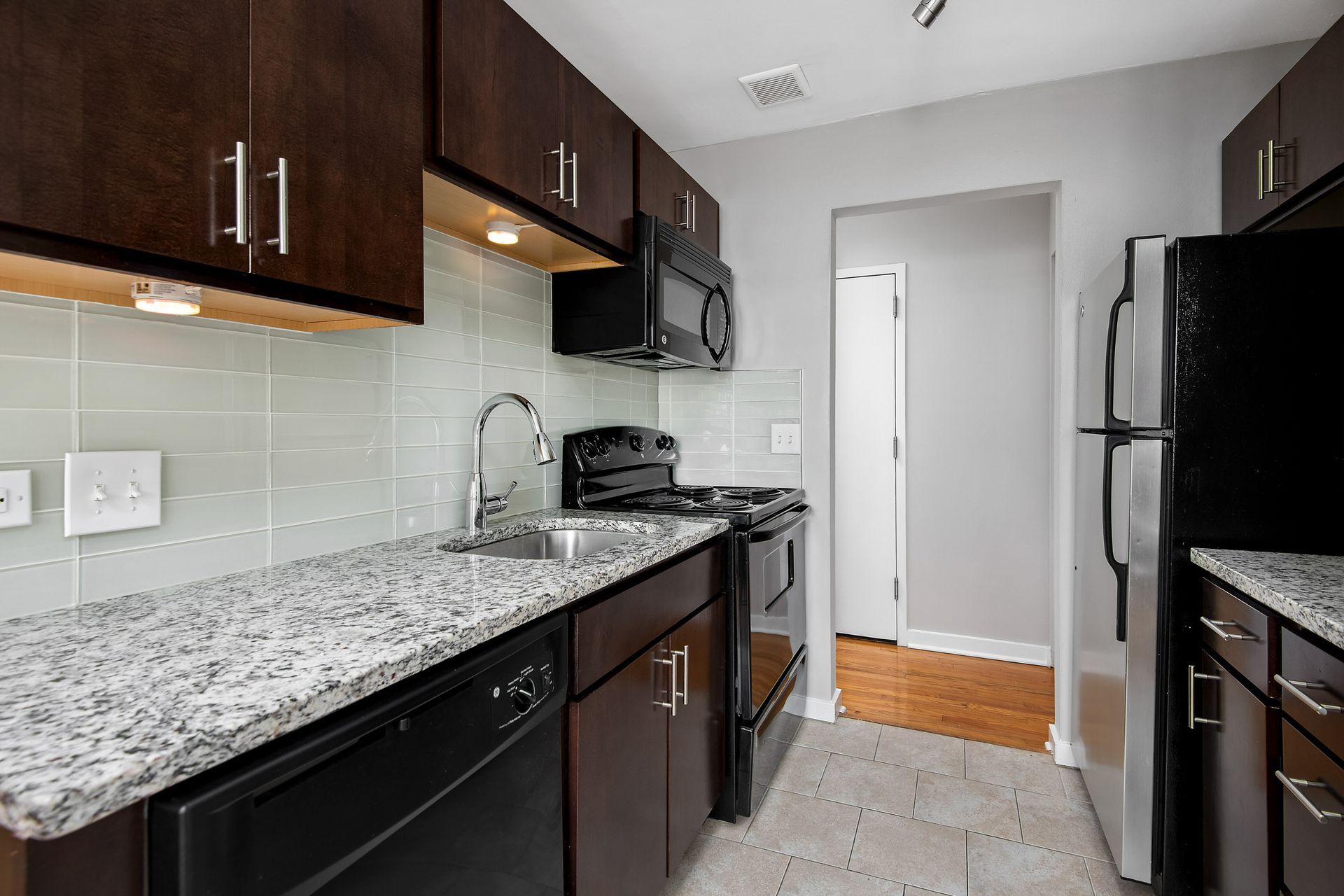 A kitchen with granite counter tops, stainless steel appliances, and black cabinets at Reside at 2727.