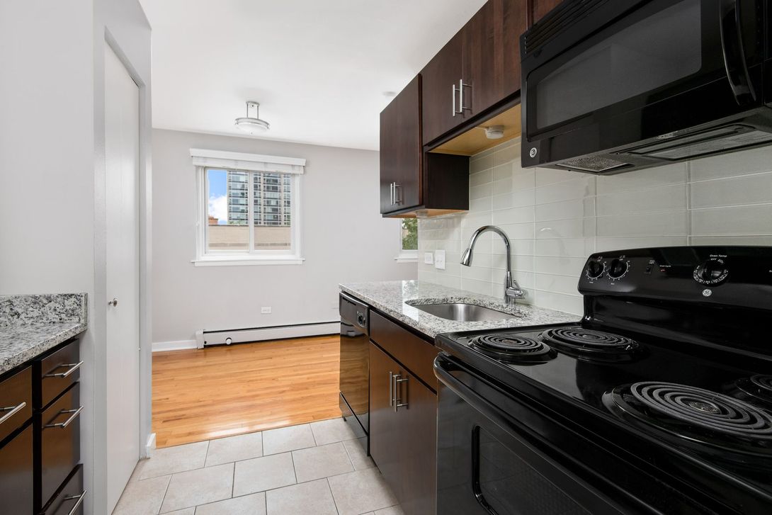 A kitchen with a stove, sink, and microwave at Reside at 2727.