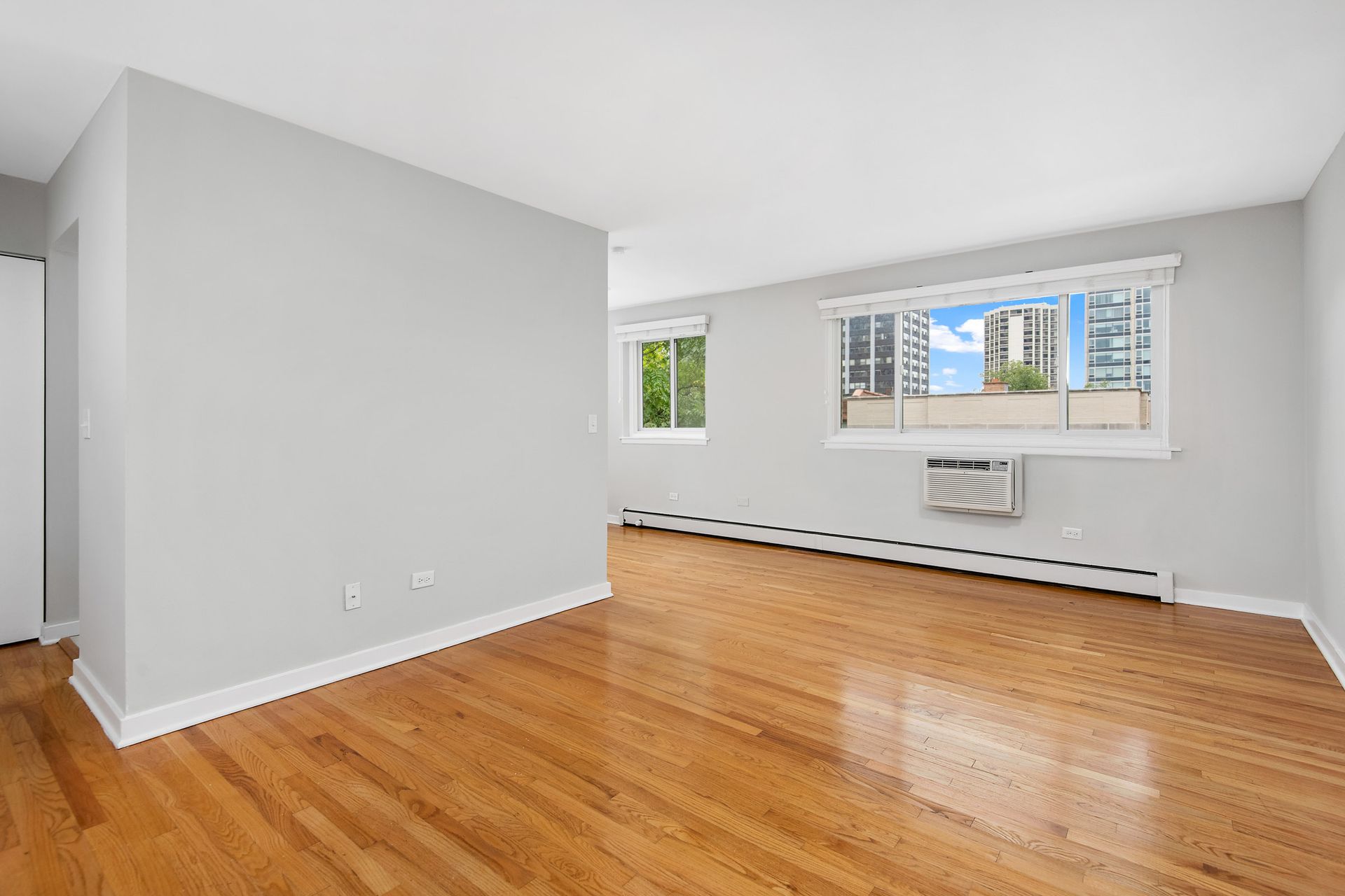An empty living room with hardwood floors and a window at Reside at 2727.