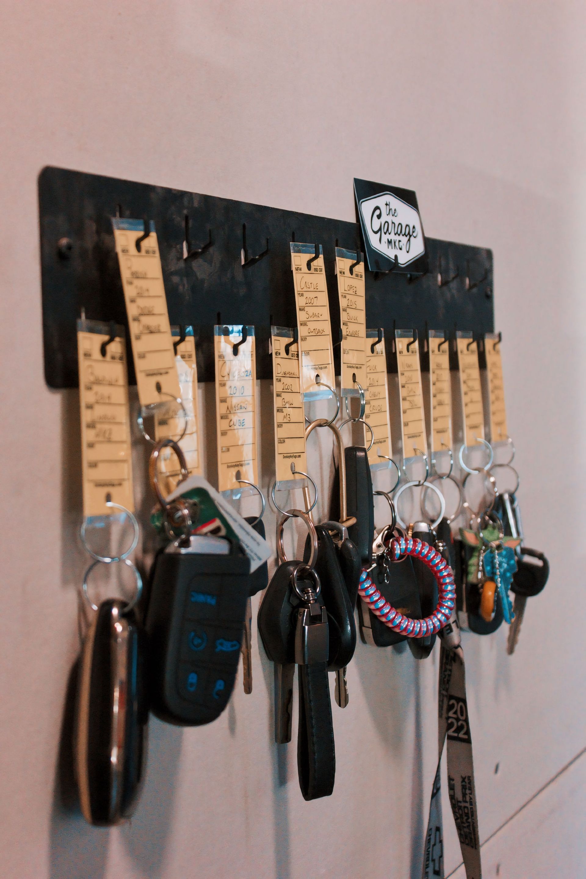 Black key holder with numerous keys hanging on it. A small sign reads 