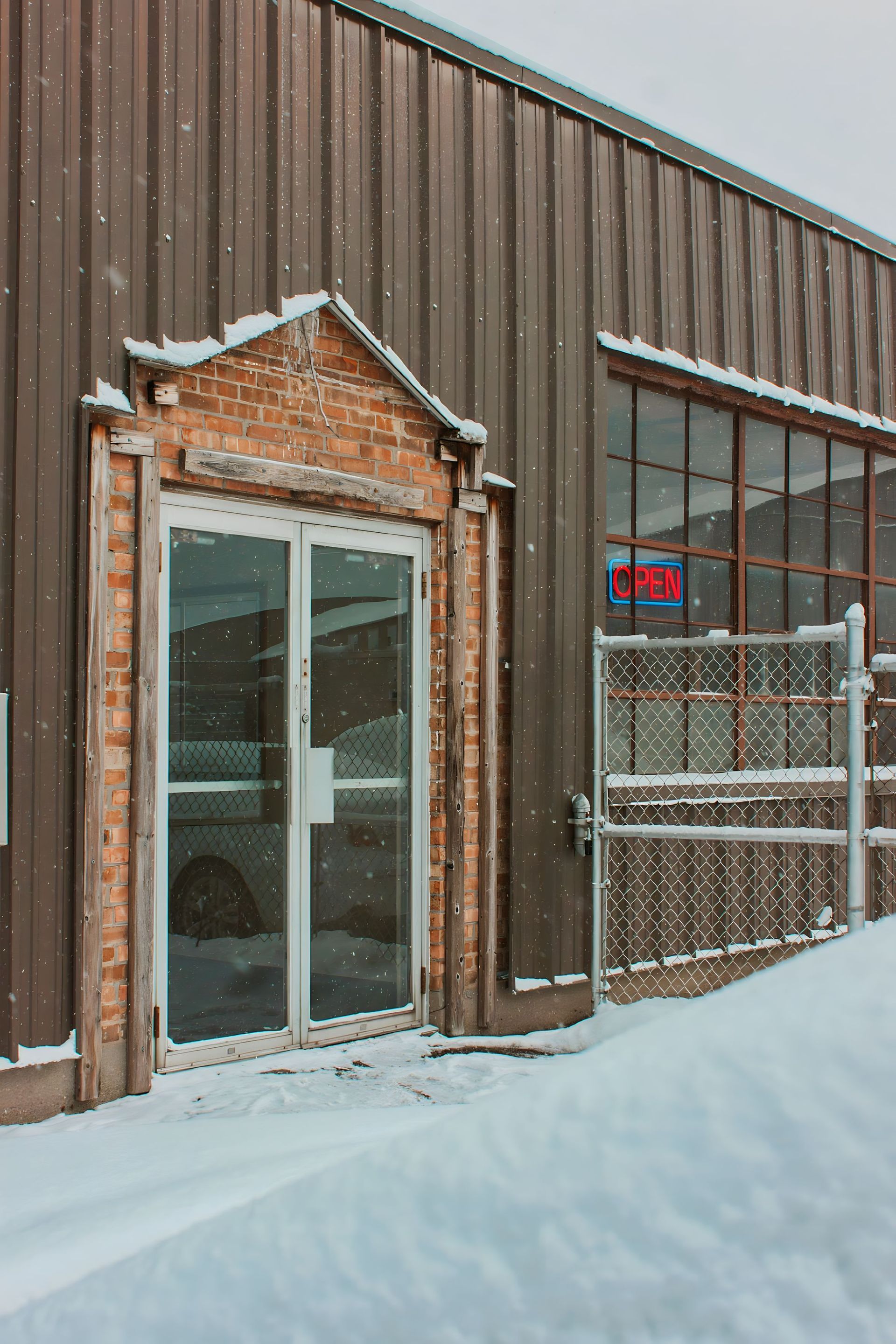 Snow-covered building exterior with a glass door and a window, a red 