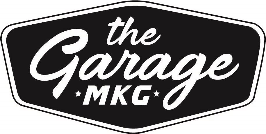 Logo for "The Garage MKG" in white script on a black hexagon with white border.