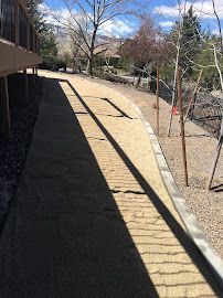 A shadow of a person is cast on a sidewalk next to a building.