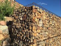 A large pile of rocks behind a wire fence.