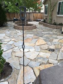 A stone patio with a bird feeder in the middle of it.