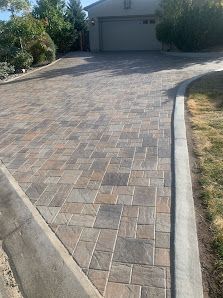A brick driveway leading to a garage with a curb.