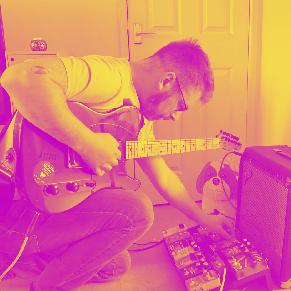 man with beard leaning over guitar effects