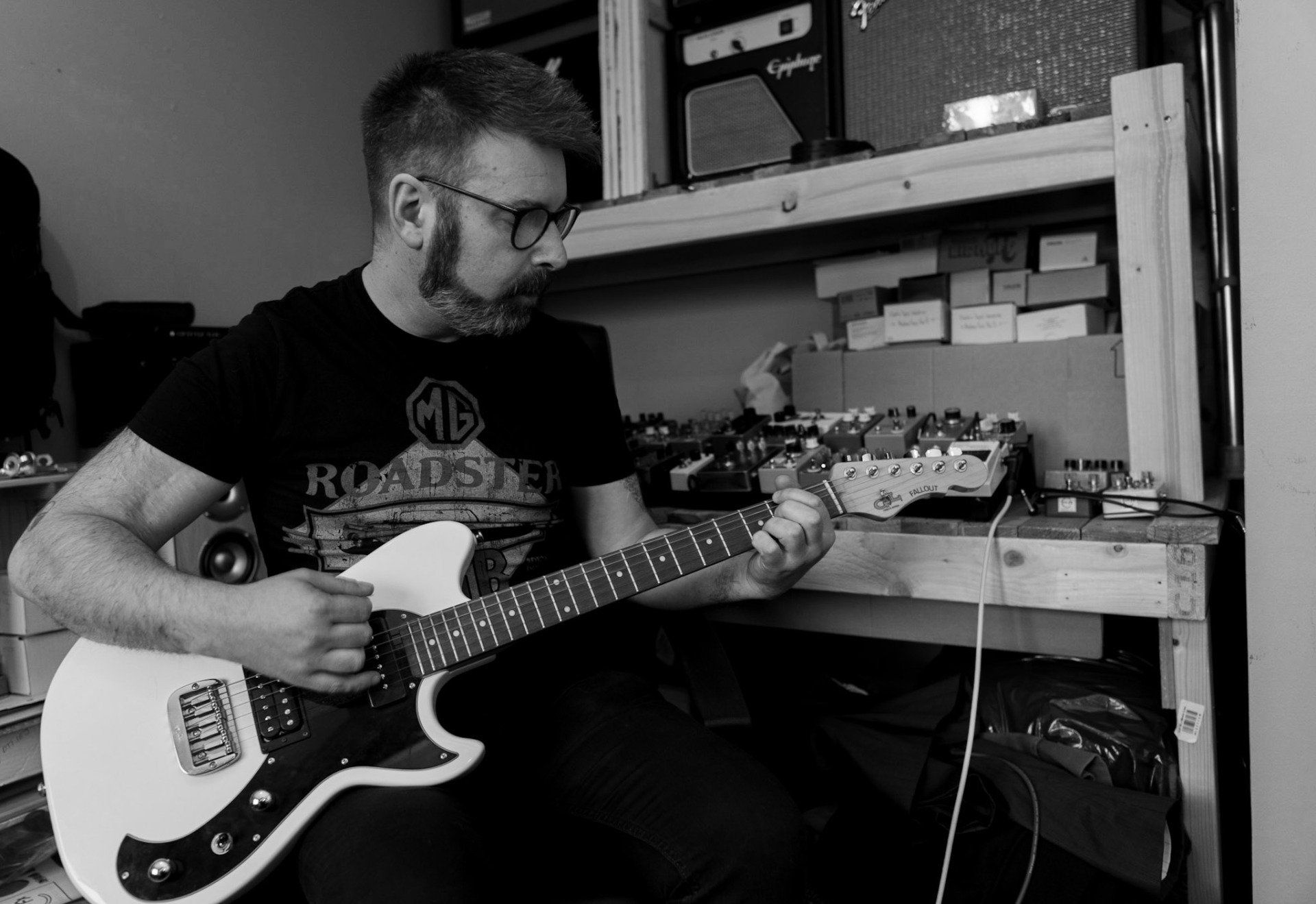 man with beard and glasses holding guitar
