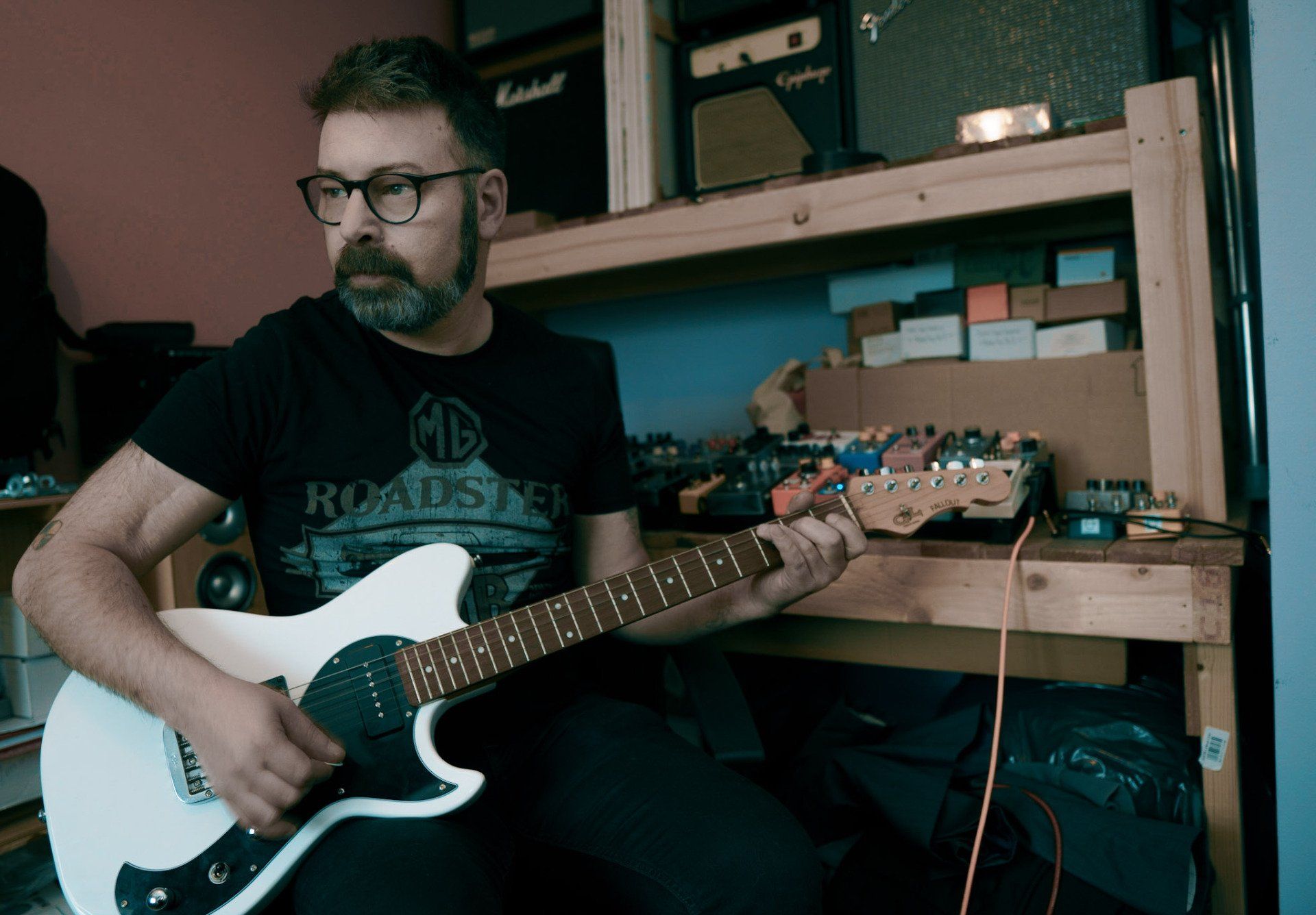 man with beard and glasses holding guitar