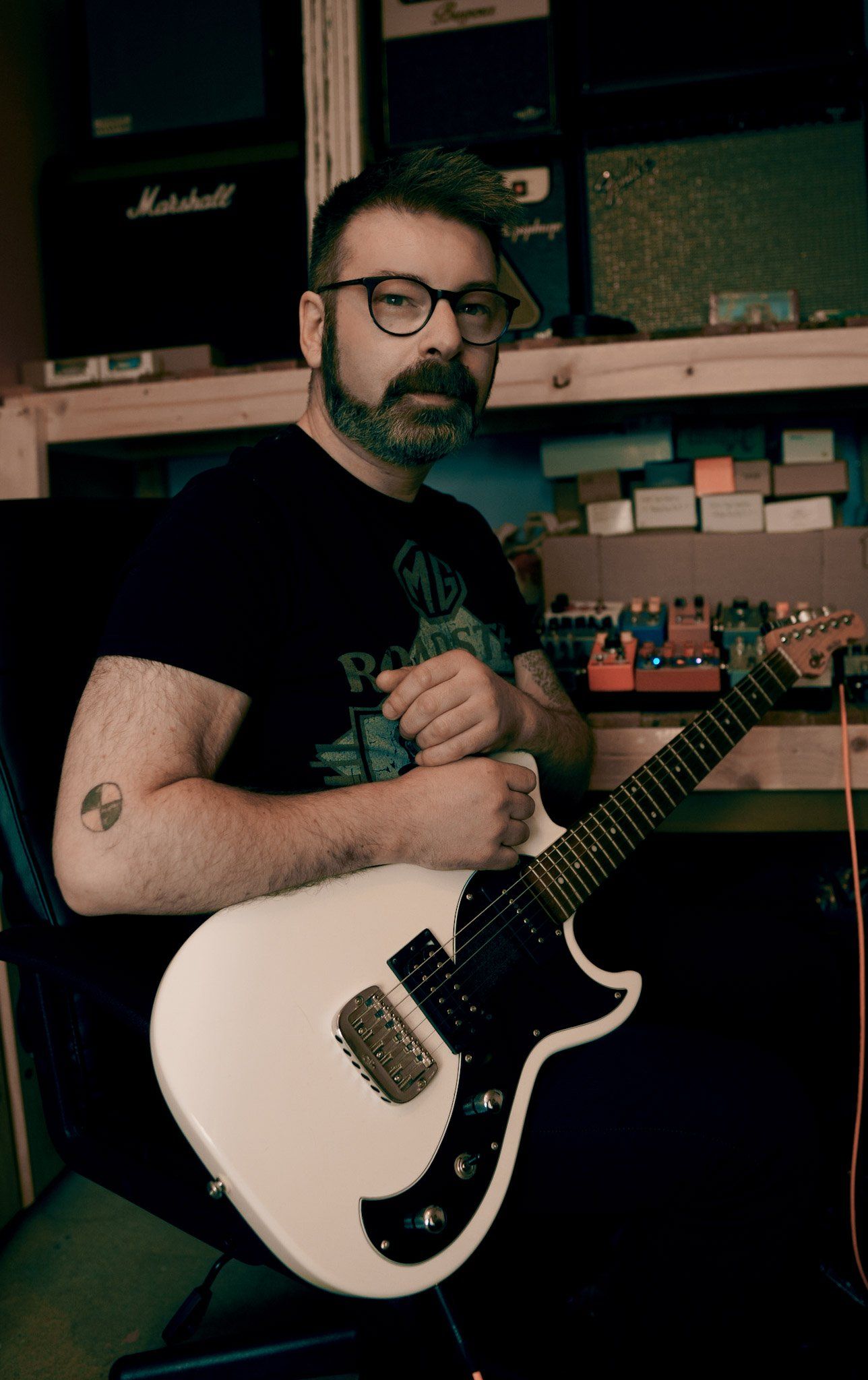 man with beard and glasses holding guitar peda