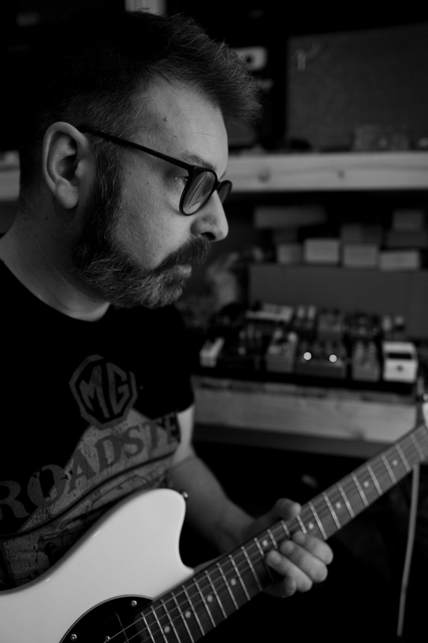 man with beard and glasses playing guitar