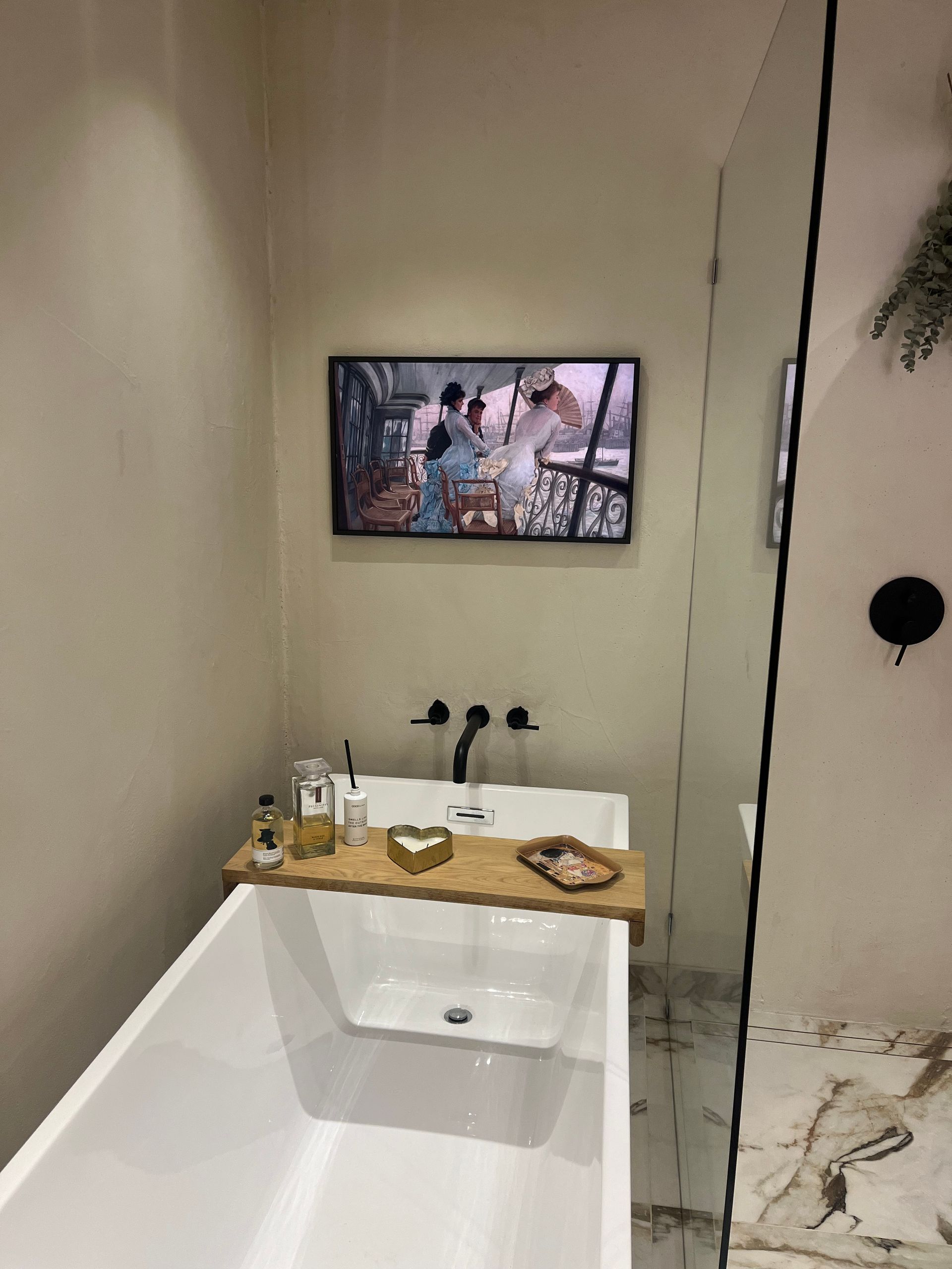 A bathroom with a bathtub and a television on the wall above it.