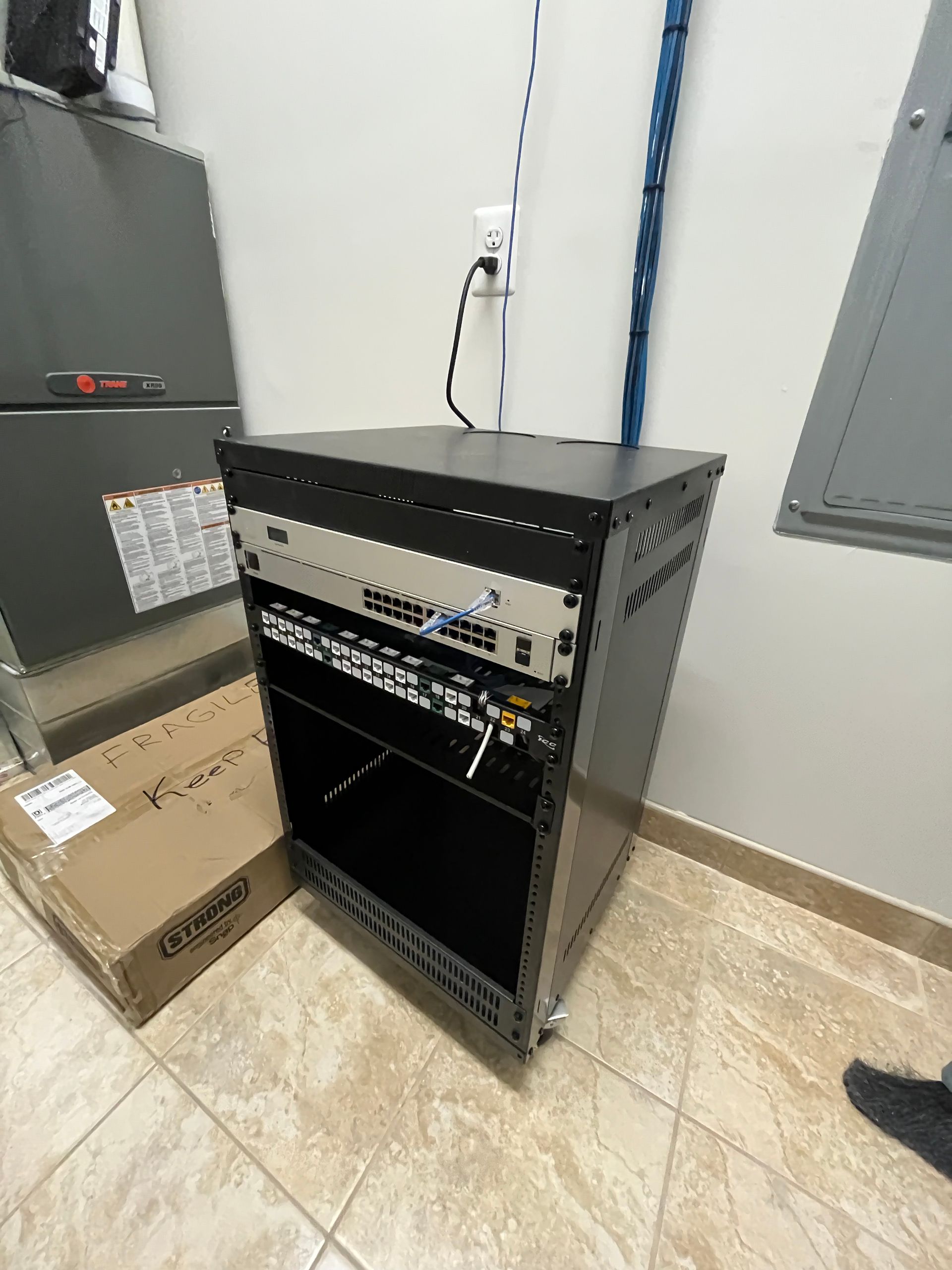 A server rack is sitting on a tiled floor in a room.