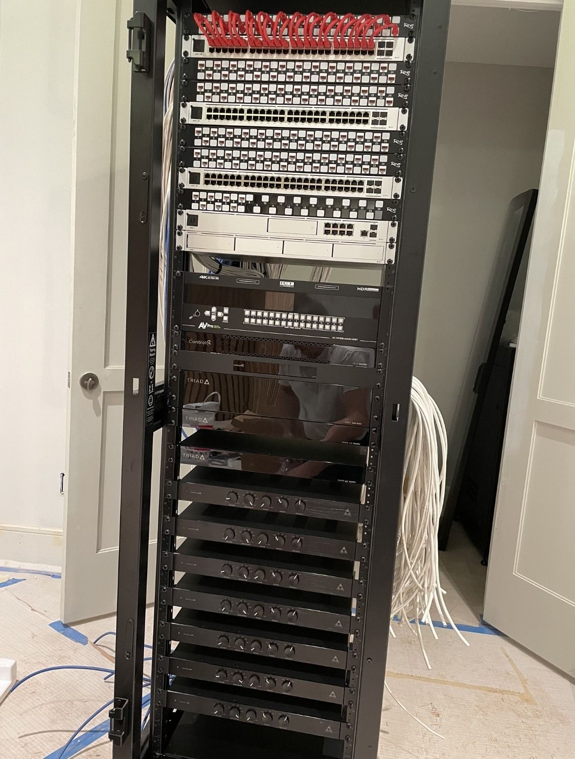 A server rack is sitting in a room next to a door.