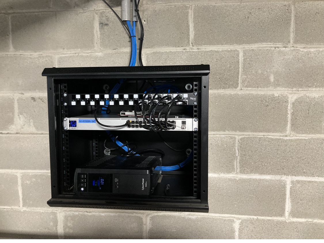 A brick wall with a black box with a lot of wires coming out of it.