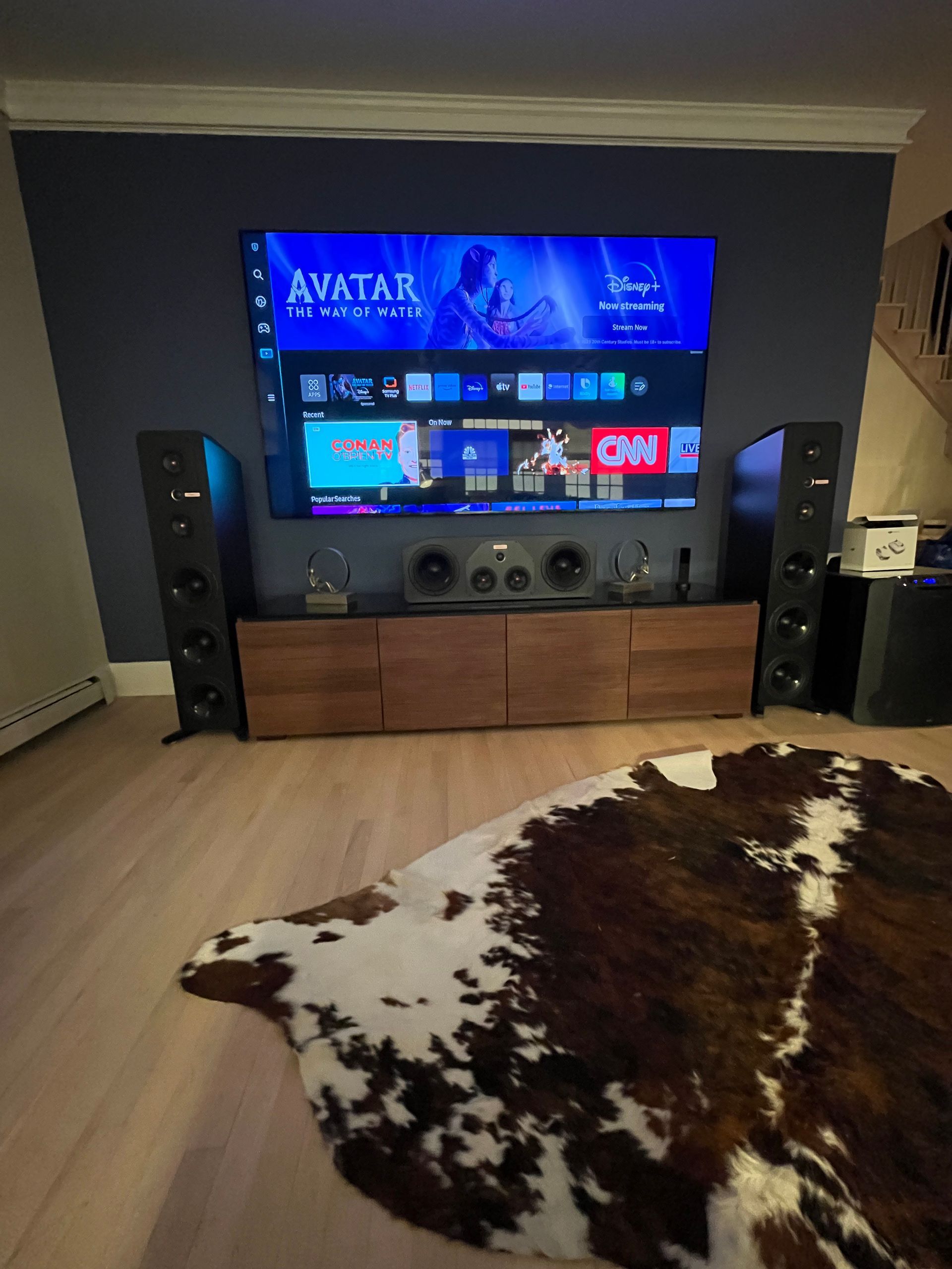 A living room with a cowhide rug and a flat screen tv.