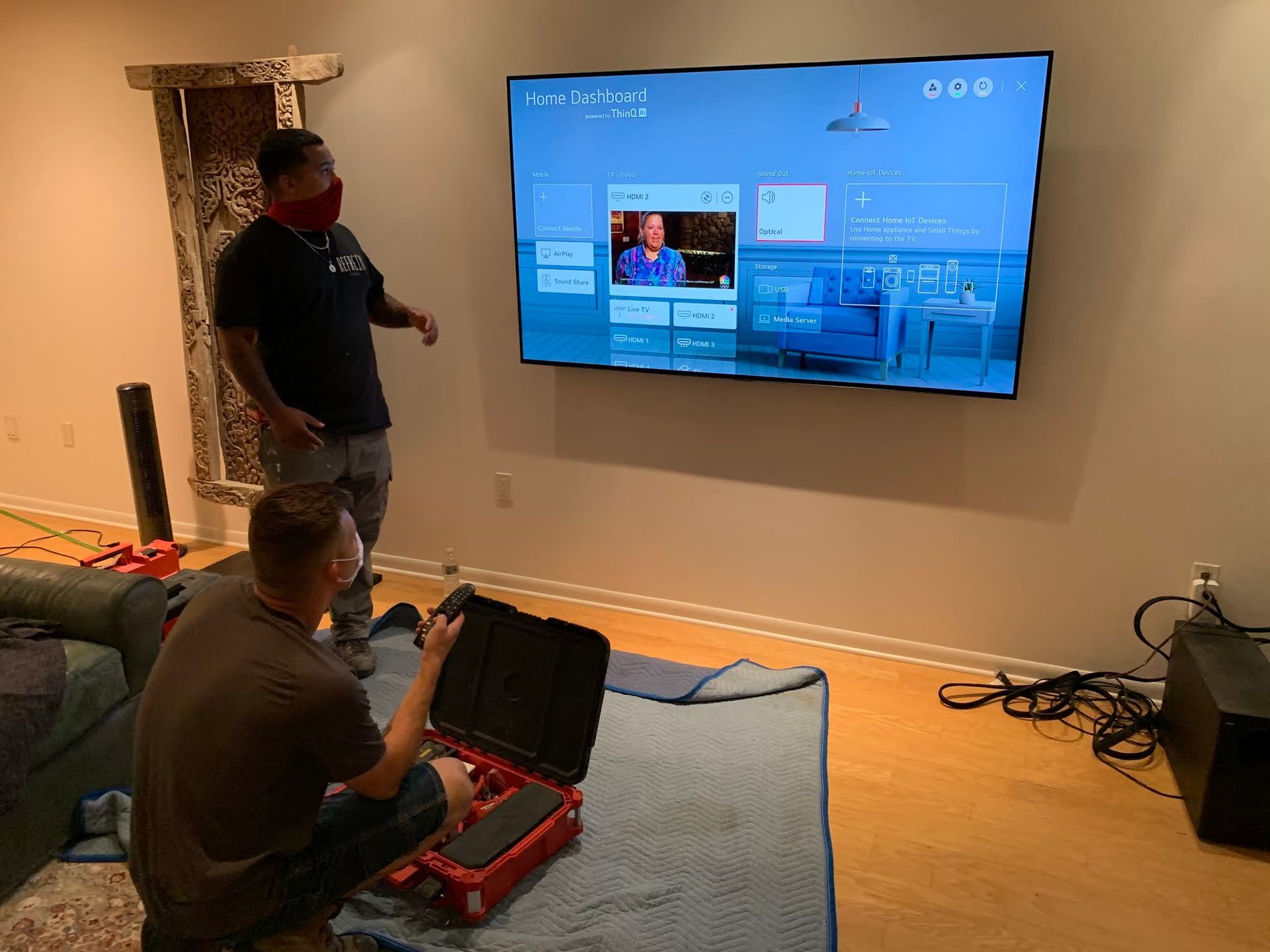 Two men are working on a flat screen tv in a living room.